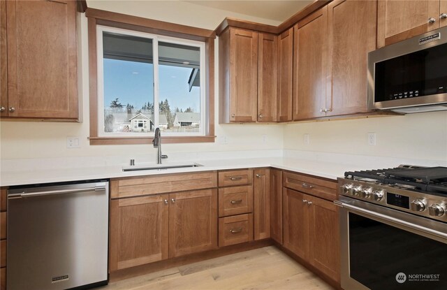 kitchen featuring appliances with stainless steel finishes, light hardwood / wood-style floors, and sink