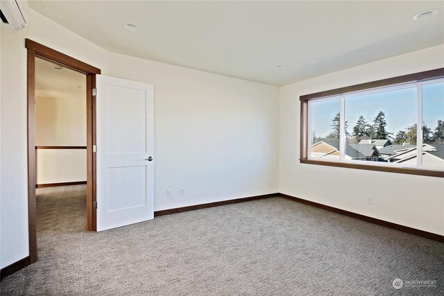 spare room featuring a wall mounted air conditioner and carpet