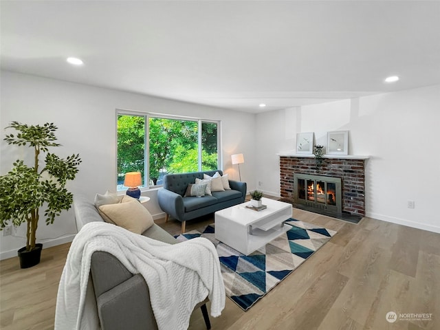 living room featuring a brick fireplace and light hardwood / wood-style floors