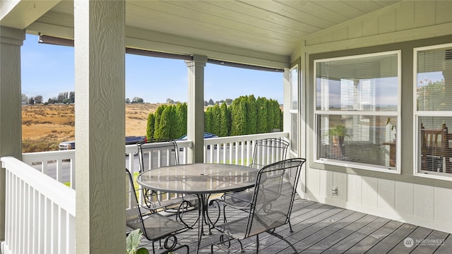 sunroom with vaulted ceiling and a rural view