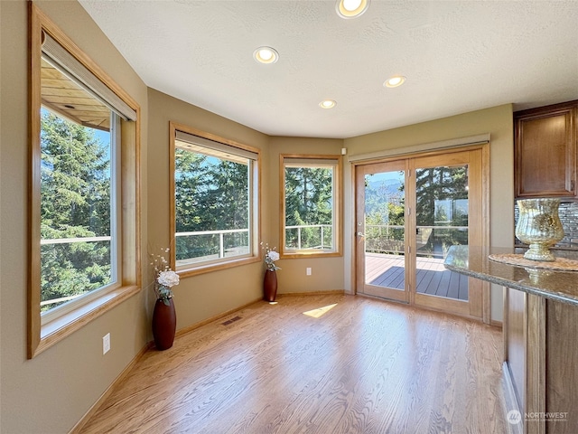 interior space with light hardwood / wood-style floors, a textured ceiling, and stone counters