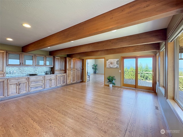 unfurnished living room featuring a textured ceiling, beamed ceiling, and light hardwood / wood-style flooring