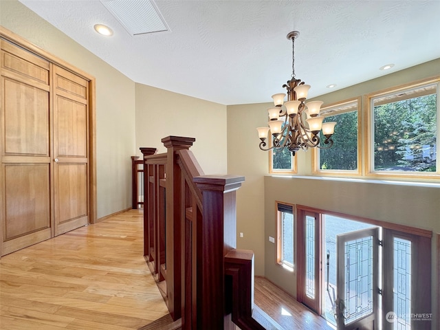 interior space featuring light wood-type flooring, a textured ceiling, and a chandelier