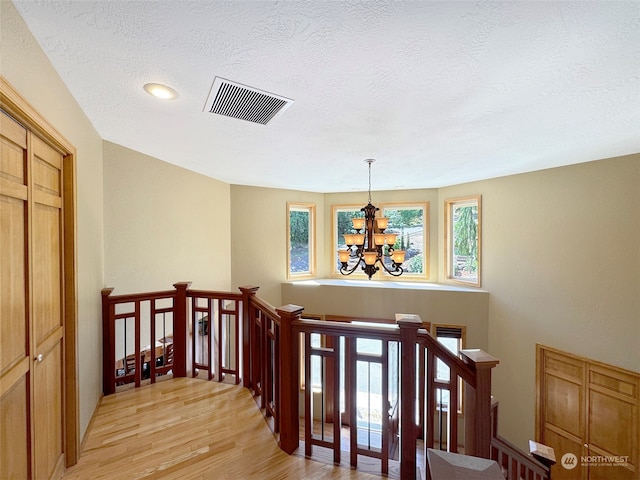 staircase with a textured ceiling, a notable chandelier, and hardwood / wood-style floors