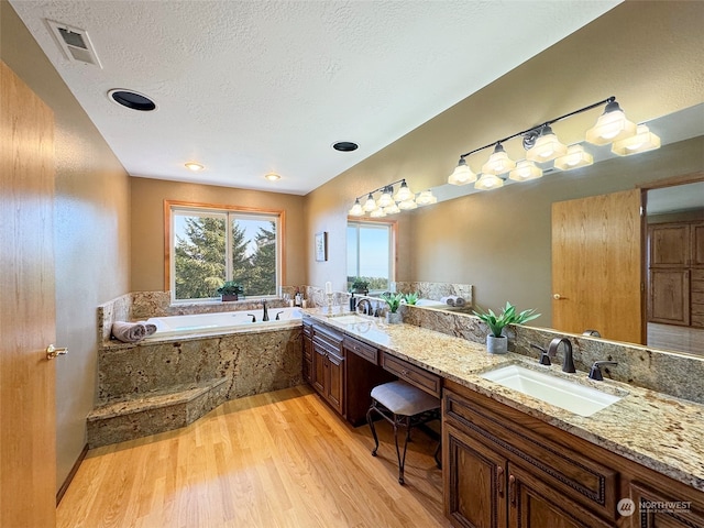 bathroom with a textured ceiling, a tub, vanity, and hardwood / wood-style flooring