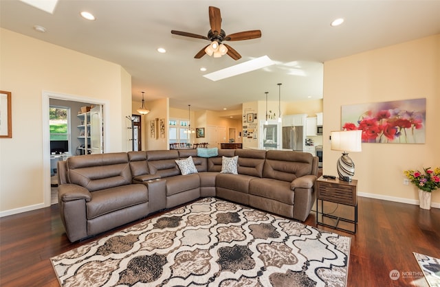 living room featuring dark hardwood / wood-style flooring, a skylight, and ceiling fan