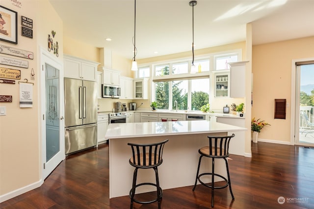kitchen featuring a breakfast bar, glass insert cabinets, stainless steel appliances, and light countertops