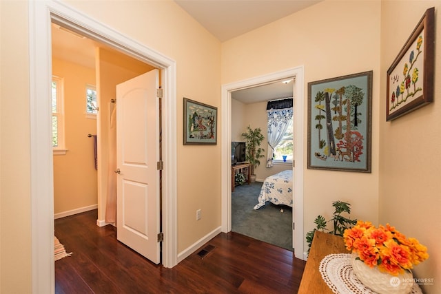 hall featuring visible vents, dark wood finished floors, and baseboards