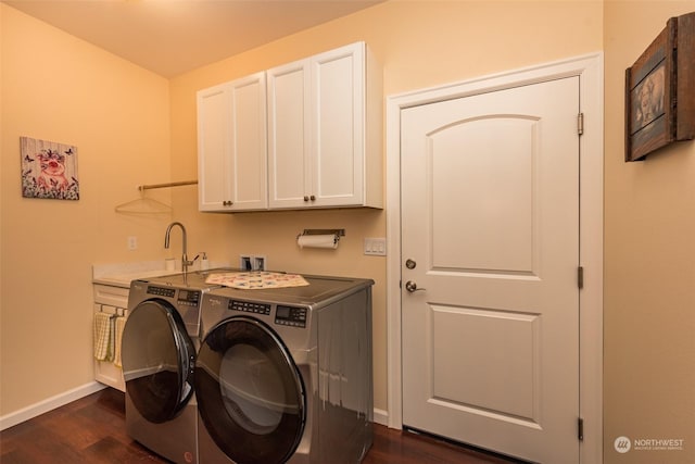 laundry room featuring washing machine and dryer, a sink, baseboards, cabinet space, and dark wood finished floors