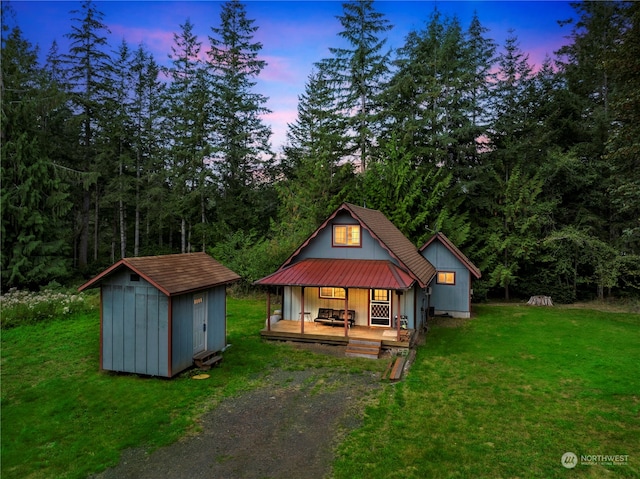 bungalow-style home with a storage shed, a lawn, and covered porch