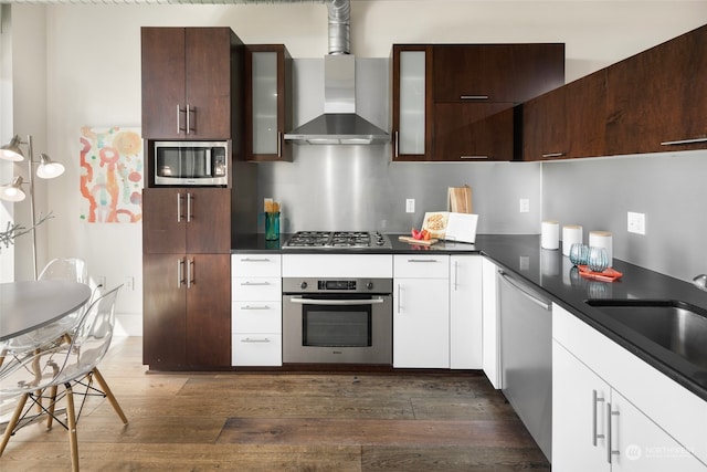 kitchen with dark brown cabinets, dark hardwood / wood-style floors, white cabinets, wall chimney exhaust hood, and appliances with stainless steel finishes