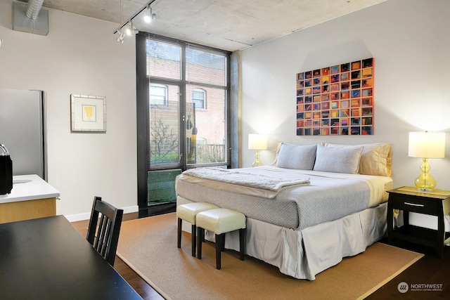 bedroom with wood-type flooring, stainless steel fridge, and rail lighting