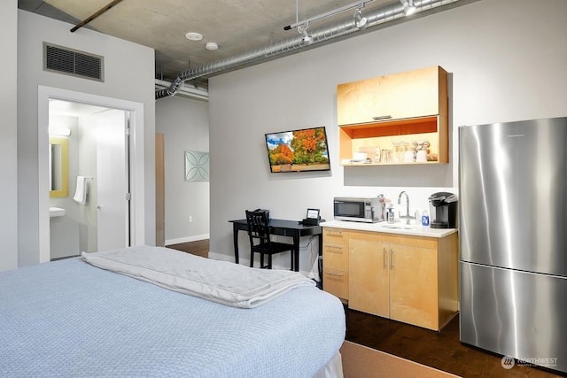 bedroom featuring stainless steel fridge, dark hardwood / wood-style floors, sink, and ensuite bathroom