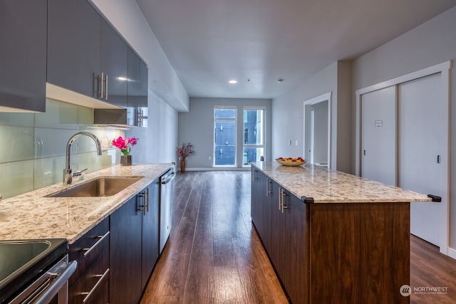 kitchen with a kitchen island, light stone countertops, dark hardwood / wood-style flooring, stainless steel dishwasher, and sink