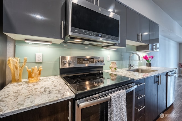 kitchen featuring light stone countertops, dark hardwood / wood-style flooring, appliances with stainless steel finishes, tasteful backsplash, and sink