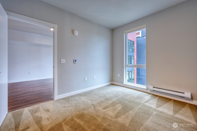 spare room featuring a baseboard radiator and hardwood / wood-style flooring