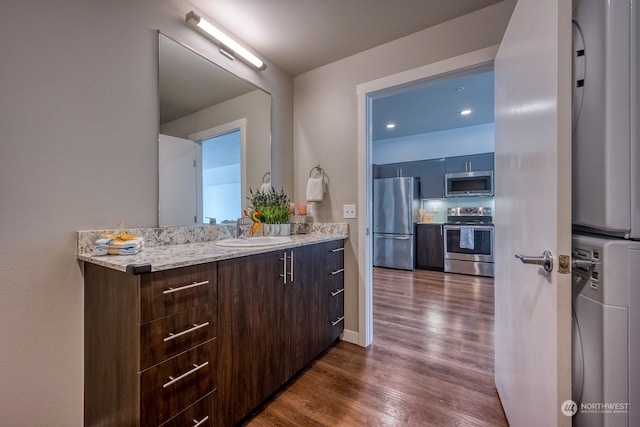 bathroom with hardwood / wood-style floors, stacked washer and clothes dryer, and vanity