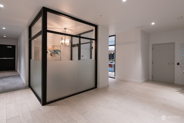 hallway featuring an inviting chandelier and light hardwood / wood-style flooring