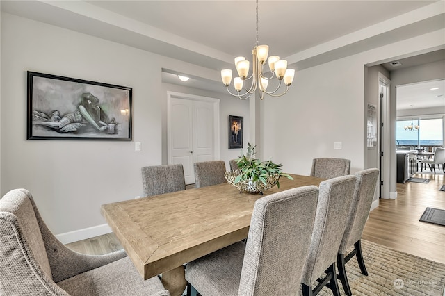 dining space featuring light wood-type flooring and a chandelier