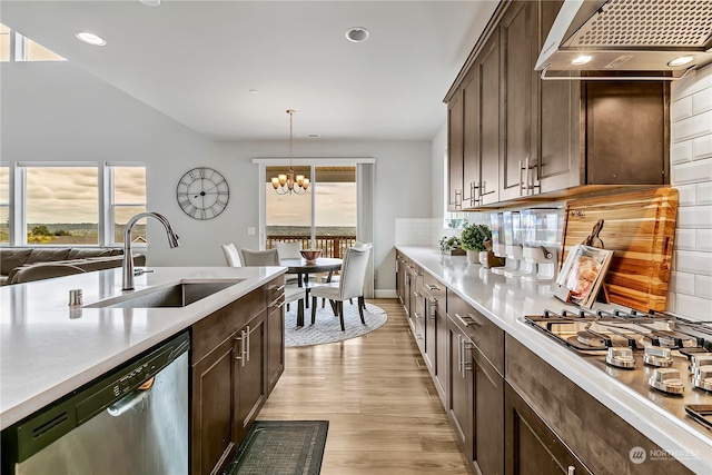 kitchen featuring stainless steel appliances, sink, a healthy amount of sunlight, and wall chimney range hood