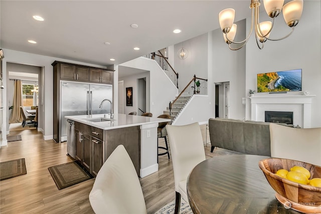 dining space featuring a chandelier, recessed lighting, stairway, light wood finished floors, and a glass covered fireplace