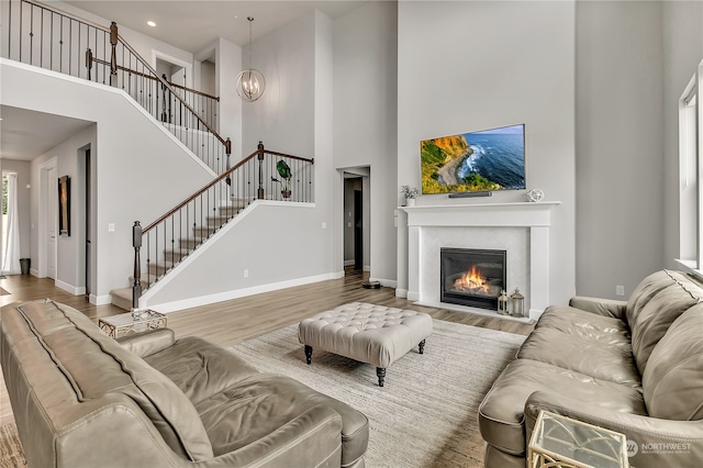 living room featuring a notable chandelier, light hardwood / wood-style floors, and a towering ceiling