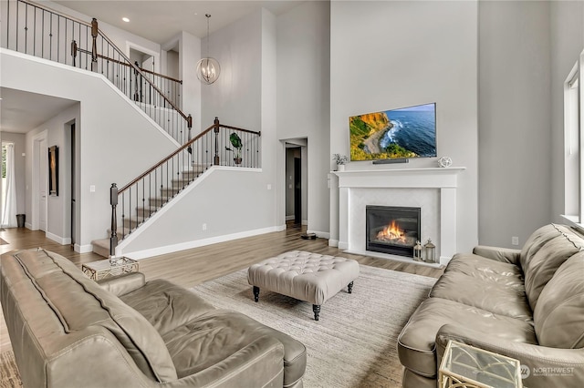 living room with a glass covered fireplace, wood finished floors, baseboards, and stairs