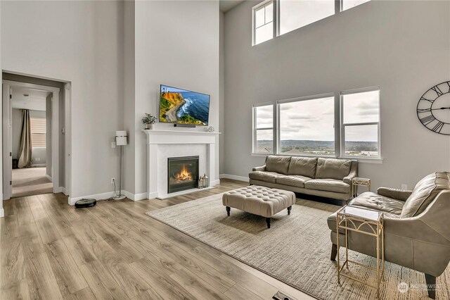 living room with a towering ceiling, light hardwood / wood-style floors, and a wealth of natural light