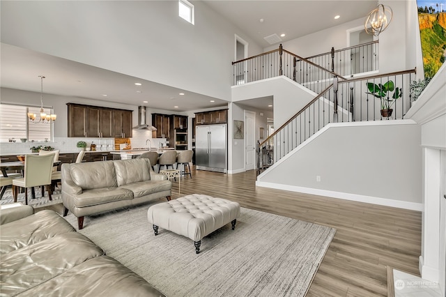 living room featuring a high ceiling, sink, light hardwood / wood-style flooring, a healthy amount of sunlight, and a chandelier