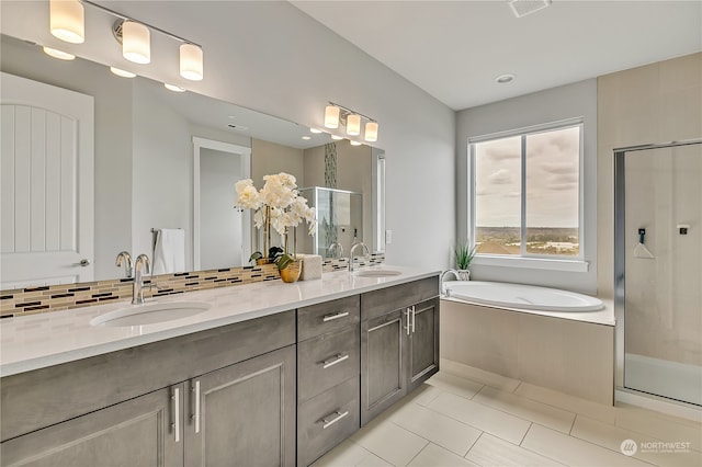 bathroom featuring plus walk in shower, vanity, tile patterned floors, and backsplash