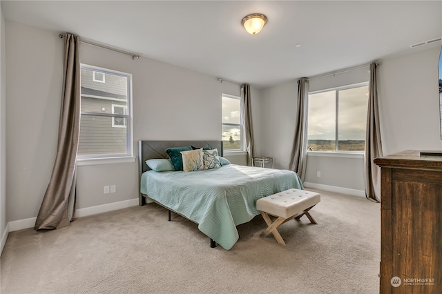 bedroom with light carpet, multiple windows, and baseboards