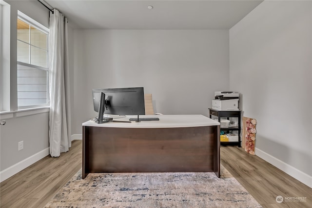 home office with light wood-style flooring and baseboards