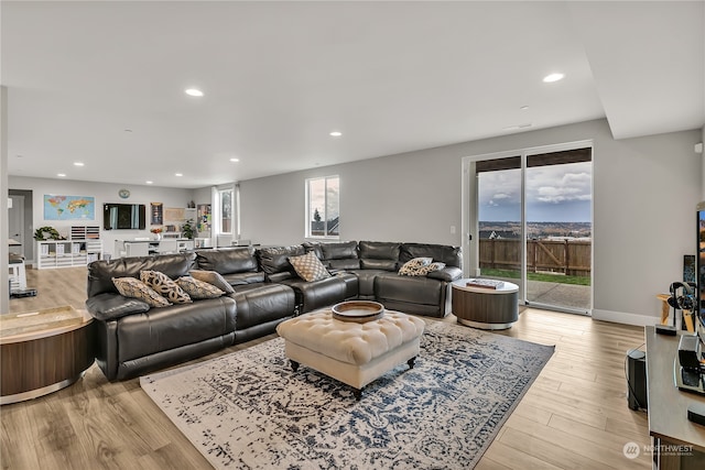 living area with baseboards, recessed lighting, and light wood-style floors