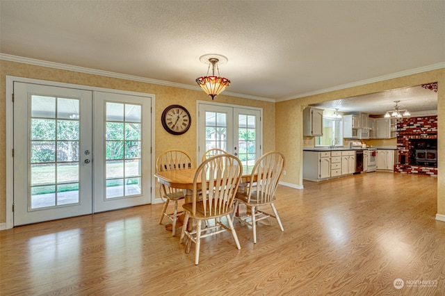 dining room with light wood-type flooring, a wealth of natural light, french doors, and a textured ceiling