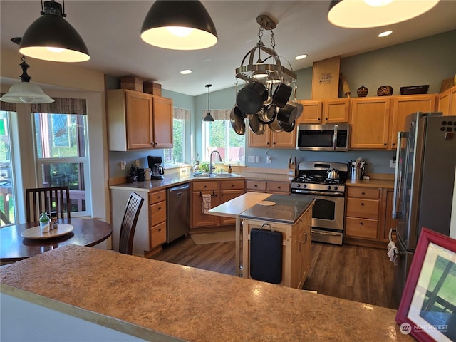 538 Canal Dr NE, Ocean Shores, WA 98569 - kitchen featuring decorative light fixtures, dark wood-style flooring, a sink, a kitchen island, and stainless steel appliances