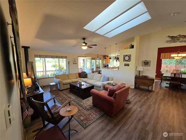 living room featuring ceiling fan with notable chandelier, hardwood / wood-style floors, and vaulted ceiling with skylight