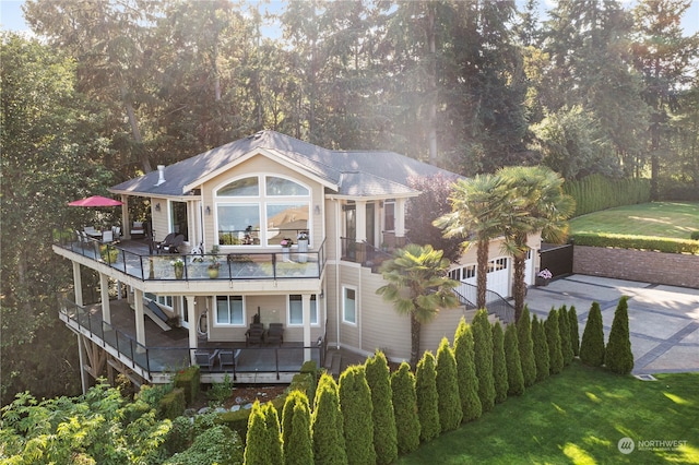 back of house with a yard, a garage, and a balcony