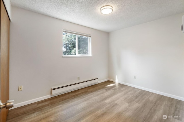 116 173rd St S, Spanaway, WA 98387 - unfurnished room featuring a textured ceiling, a baseboard heating unit, baseboards, and wood finished floors