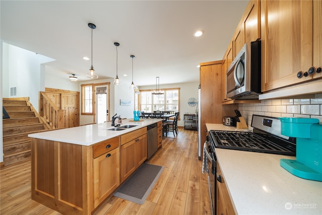 kitchen with an island with sink, light hardwood / wood-style flooring, stainless steel appliances, and sink