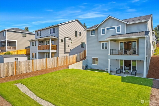 rear view of property featuring a balcony, a patio area, and a lawn