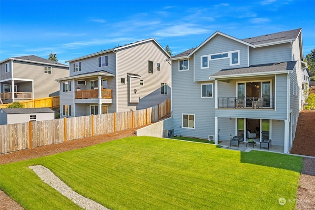 back of property featuring fence, roof with shingles, a residential view, a patio area, and a lawn