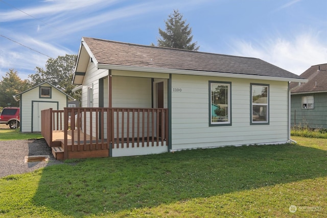 view of front of home with a storage shed, a wooden deck, and a front yard