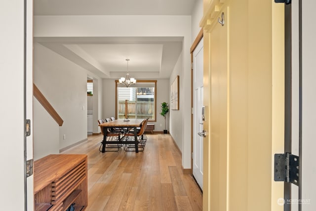 interior space with a raised ceiling, light hardwood / wood-style floors, and a notable chandelier