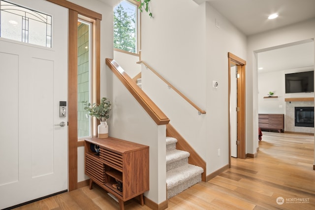 entryway with a tile fireplace and light hardwood / wood-style flooring