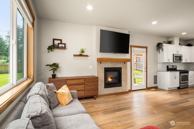 living room featuring a tiled fireplace and light hardwood / wood-style floors