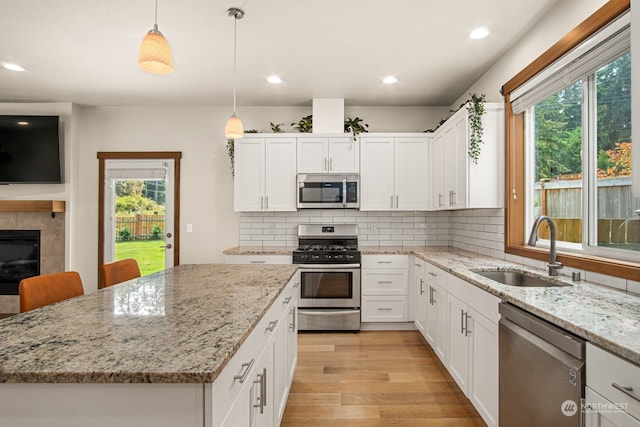 kitchen featuring appliances with stainless steel finishes, hanging light fixtures, plenty of natural light, and sink