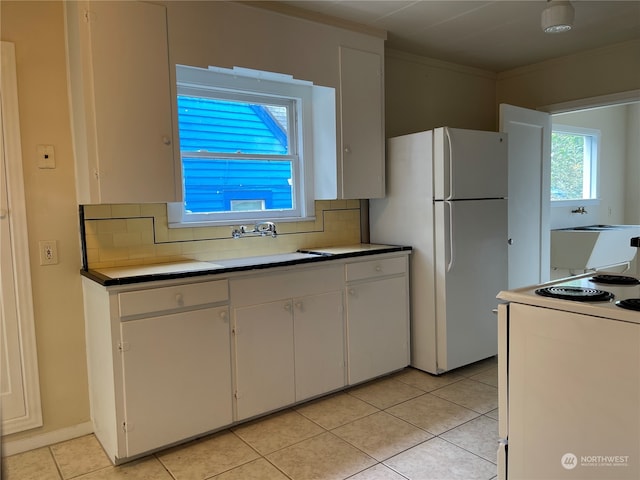 kitchen with decorative backsplash, white appliances, light tile patterned floors, and white cabinets