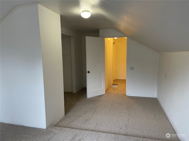 bonus room featuring a textured ceiling, lofted ceiling, and carpet flooring