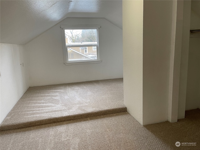 bonus room with a textured ceiling, lofted ceiling, and carpet flooring