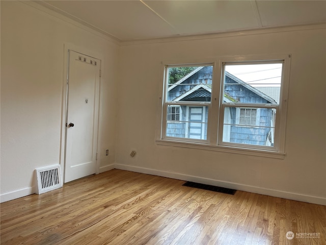 spare room with ornamental molding and light wood-type flooring